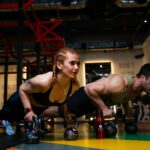 a man and a woman doing push ups with dumbbells